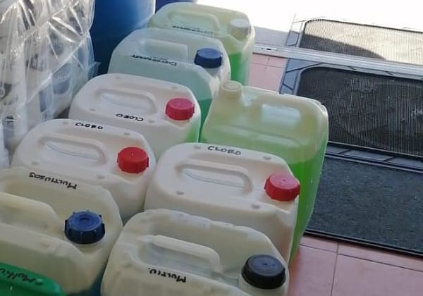 Twenty-litre containers marked bleach, multipurpose and detergent, ready to be dispensed.