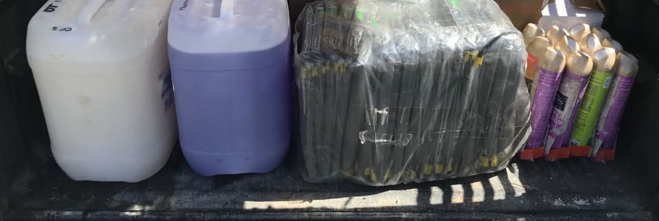 A truck bed loaded with 20-litre containers and consumables for a delivery run.